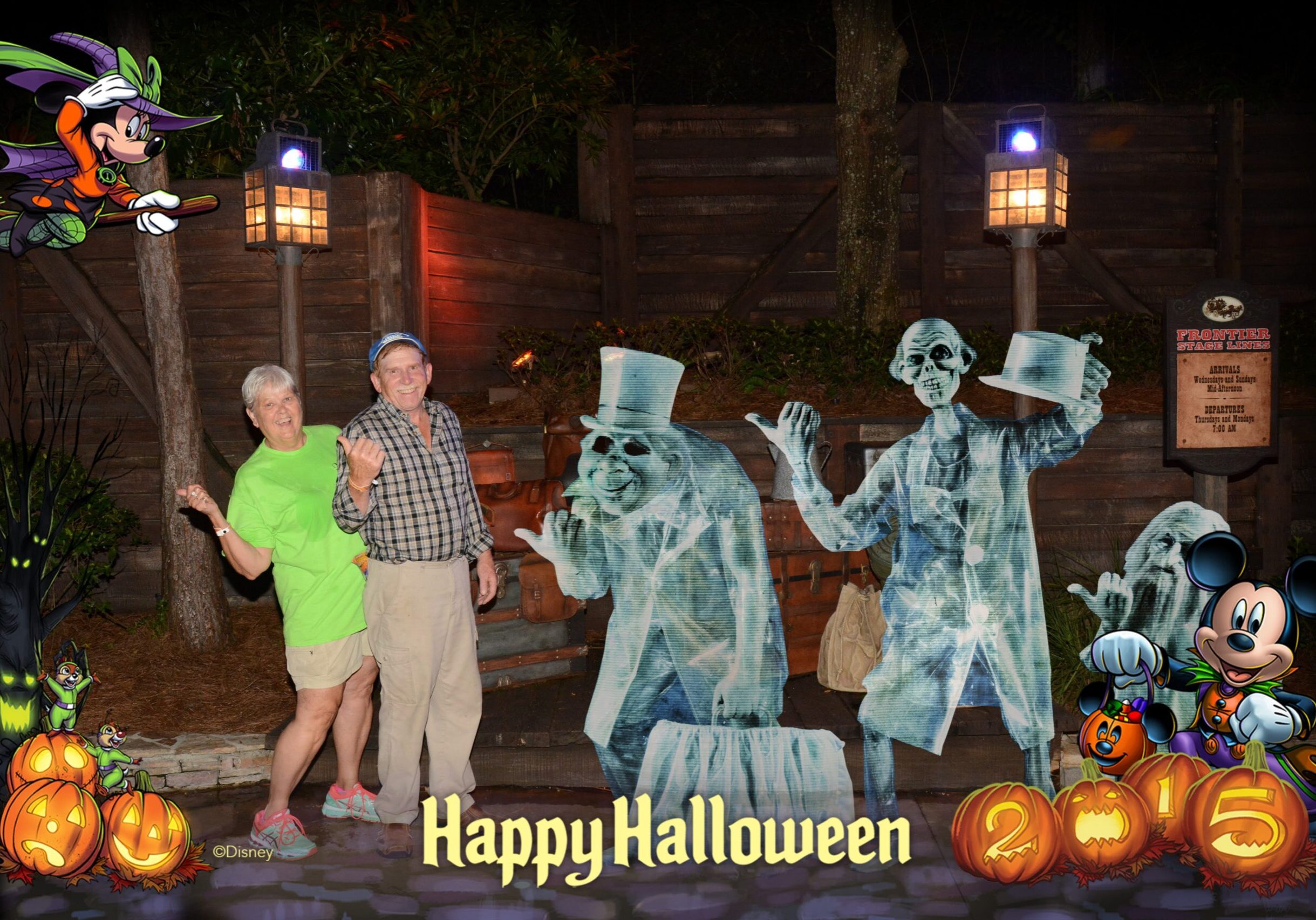 A smiling couple poses at night beside Disney’s animated Hitchhiking Ghosts from the Haunted Mansion during Mickey’s Not-So-Scary Halloween Party. The photo is framed with Halloween decorations, including pumpkins, Minnie Mouse flying on a broomstick, and Mickey Mouse dressed as a vampire with the text “Happy Halloween 2015.”